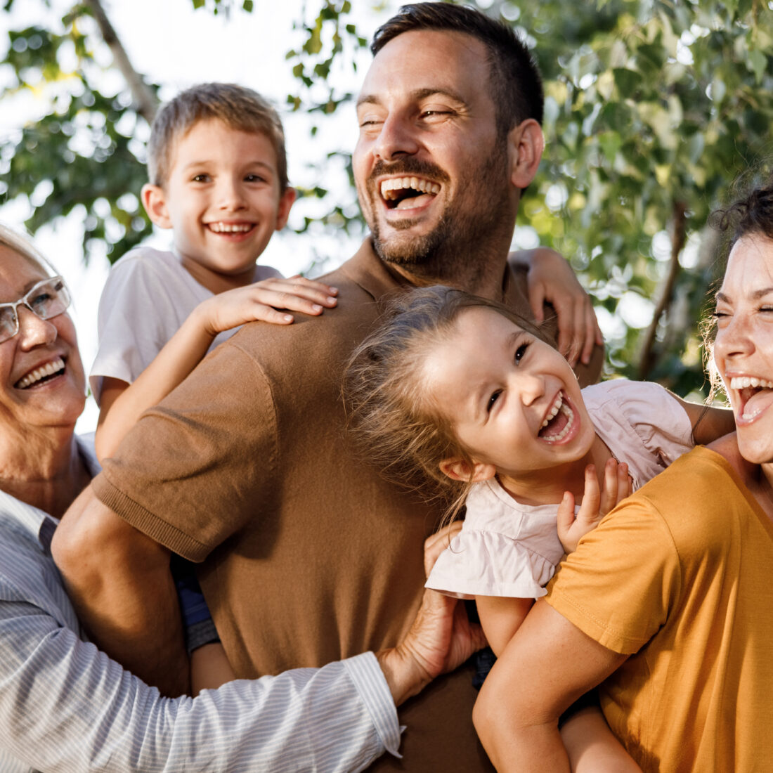 Cheerful multi-generation family having fun in nature. Parents are piggybacking their kids.